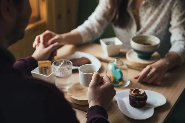 Couple holding hands over coffee during a date, symbolizing personalized matchmaking consultations and meaningful connections.